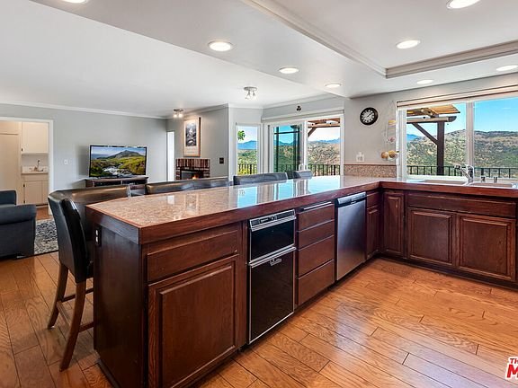 Kitchen with dark wood cabinets, steel appliances, large island with seats, and big windows with view.