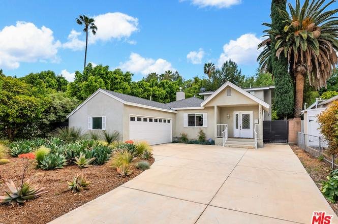 California real estate house with garage, green yard, and palm trees.