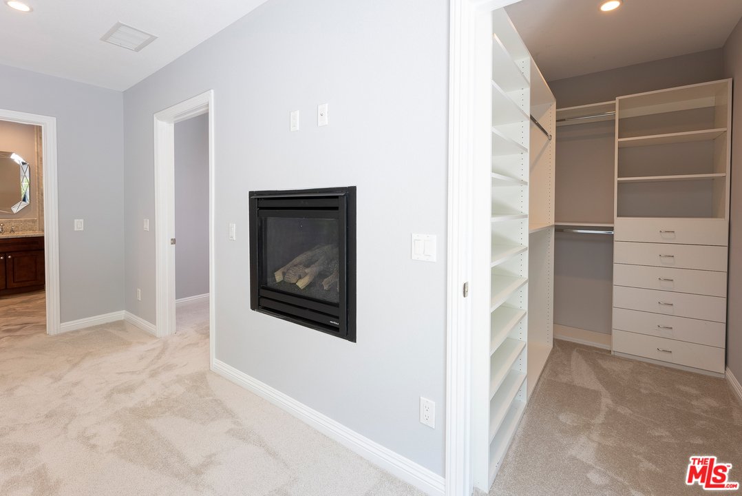 Room with fireplace, open closet shelves, gray walls, and carpet floor.