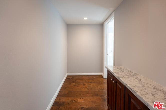 Hallway with gray walls, wood floor, marble counter, and window.