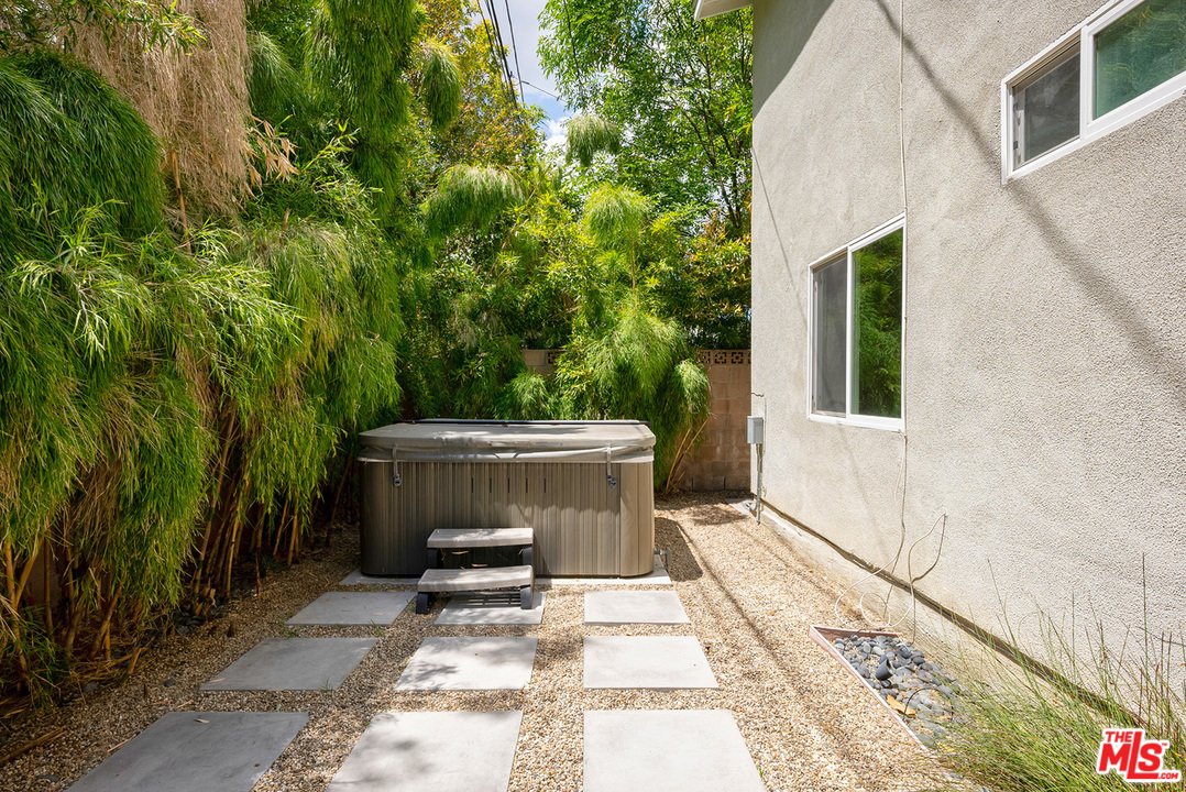 Hot tub with bamboo, gravel, stepping stones, and house.