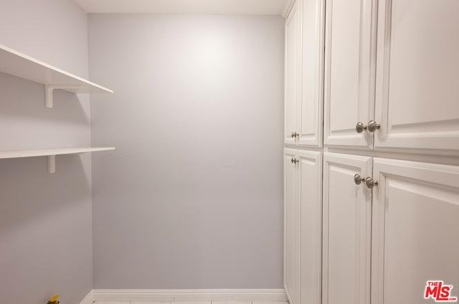 Room with gray walls, white cabinets, shelves, and tile floor.