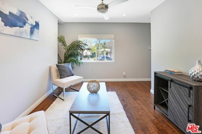 Living room with white chair, ottoman, wood coffee table, rug, and window.