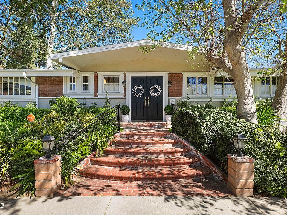 California real estate home with brick path, trees, and front stairs to door.