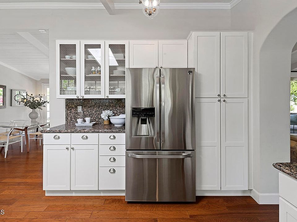 Kitchen with white cabinets, steel refrigerator, and granite counters.