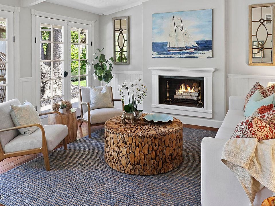 Living room with sofa, chairs, fireplace, coffee table, and large windows.