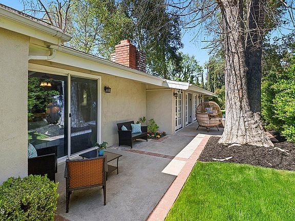 Patio with seating area, green plants, and trees California real estate.