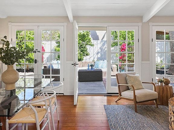 Living room with table, chairs, wooden floor, and glass doors to patio.