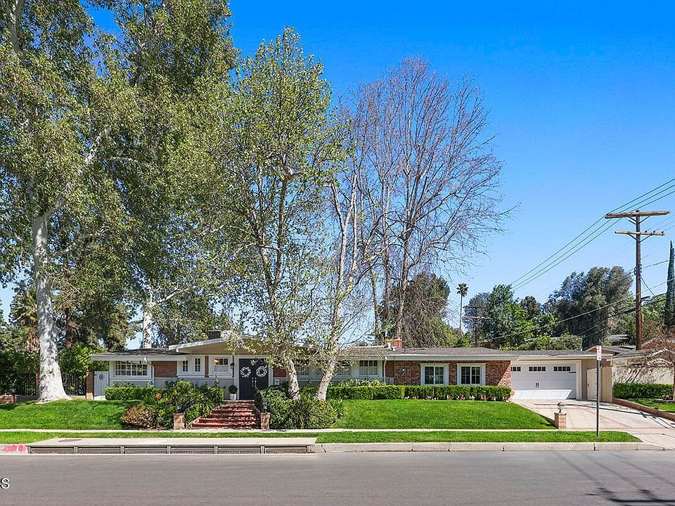 Single story house with brick front, lawn, trees, garage on a quiet street California real estate.