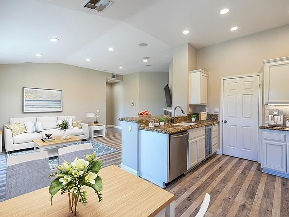 Kitchen with white cabinets, granite countertops, stainless steel appliances, and hardwood floor