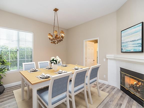 Dining room with large wooden table, eight chairs, chandelier, and fireplace