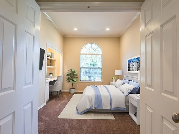 Bedroom with blue and white bed, desk with chair and bookshelf