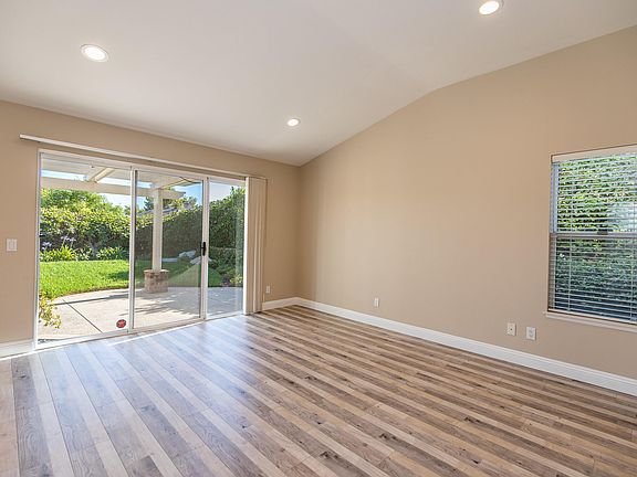 Living room with wooden floor, large windows, and sliding glass door to outdoor area