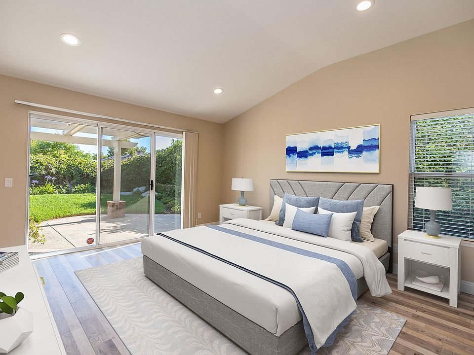 Bedroom with large blue and white bed, side tables with lamps, and abstract wall art