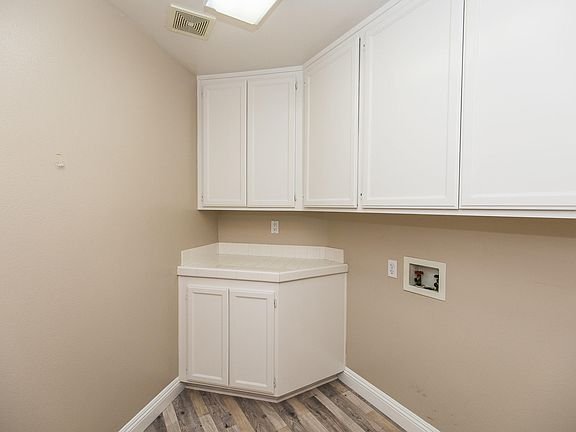 Laundry room with white cabinets, countertop, and space for washer and dryer