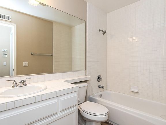 Bathroom with white bathtub, toilet, sink, and large mirror