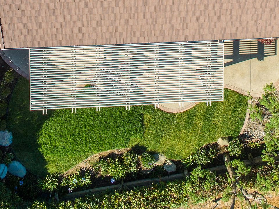 Aerial view of California real estate house with slatted roof, lawn, and garden.