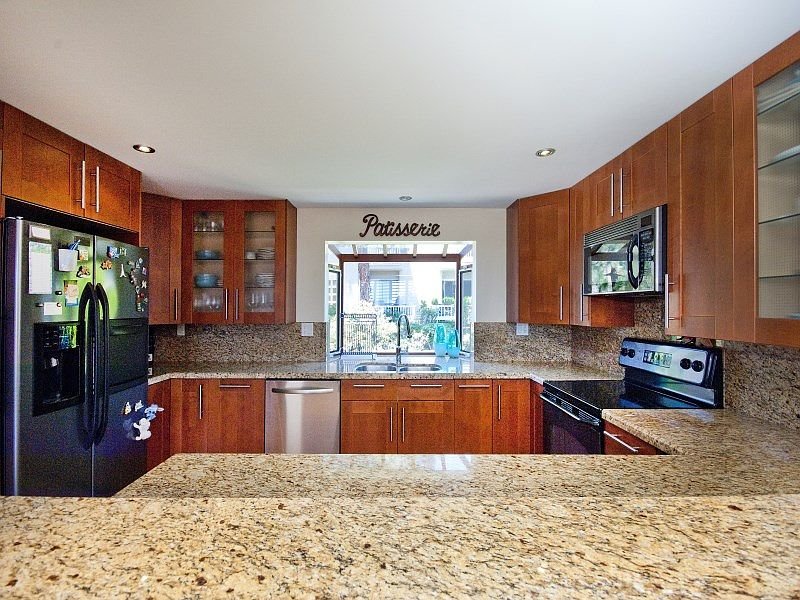 Kitchen with wooden cabinets, granite countertops, stainless steel appliances, and large window