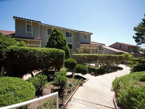 California real estate pathway with shrubs, trees, and houses