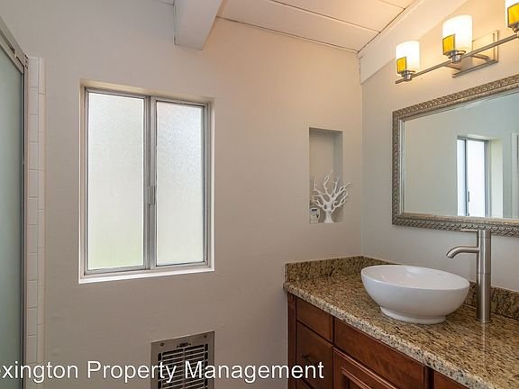 Bathroom with sink, large mirror, granite countertop, and decorative shelf with coral