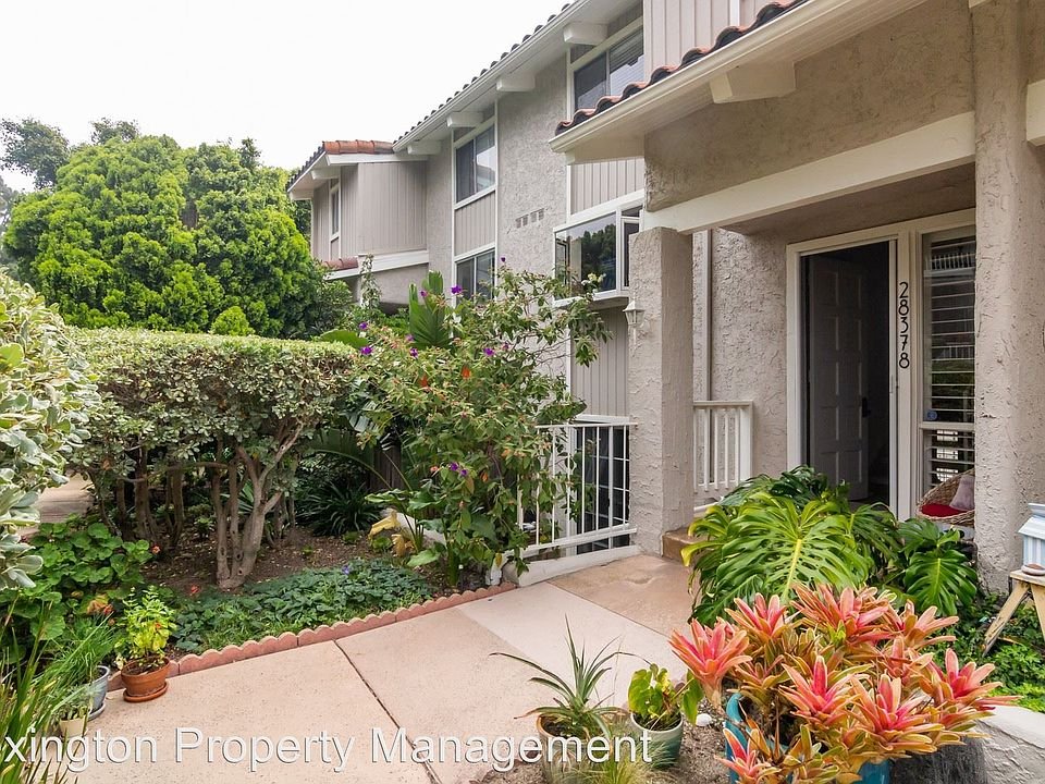 California real estate entrance with pathway, greenery, and colorful plants