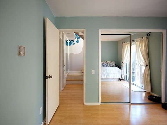 Room with sliding mirror door, hardwood floor, and staircase