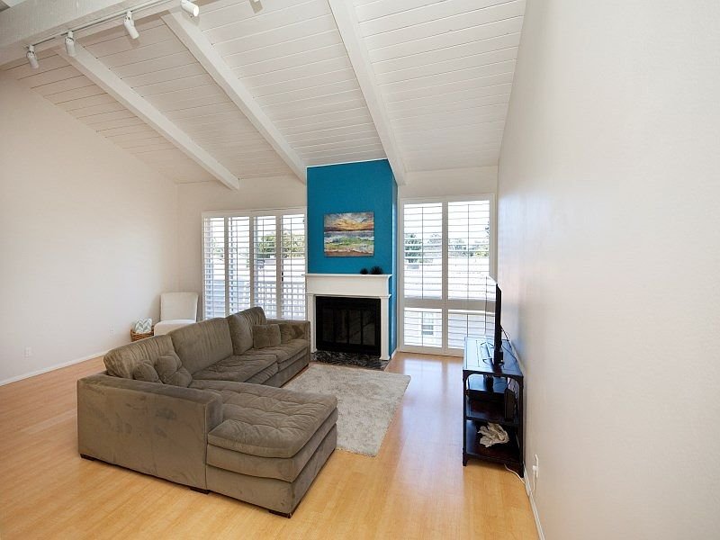 Living room with large sectional couch, fireplace, blue accent wall, TV, and light hardwood floor