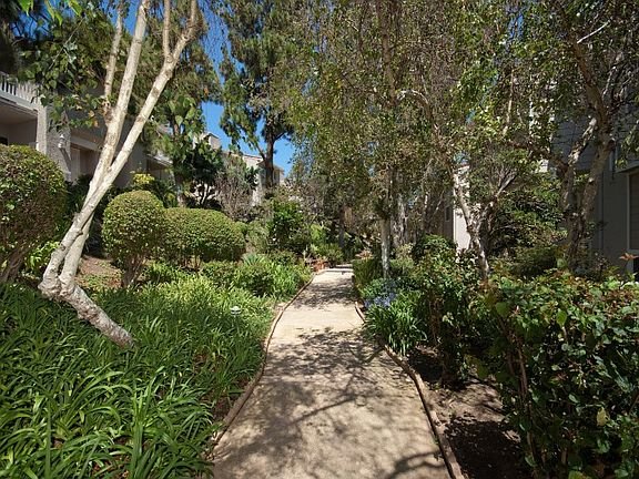 Walkway with greenery, trees, and landscaped area