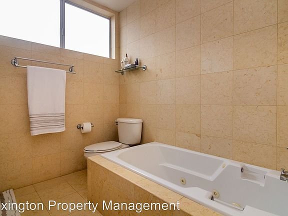 Bathroom with bathtub, toilet, towel rack, and shelf with toiletries