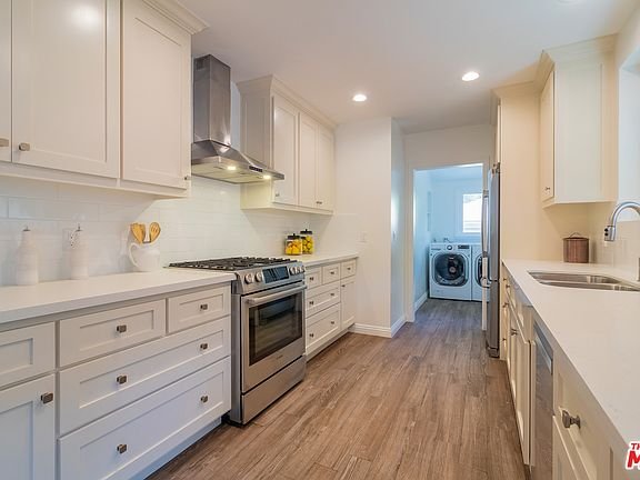 Bedroom with bed, pillows, nightstand, chair, desk, and windows.