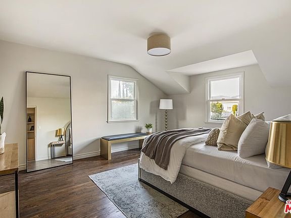 Bedroom with bed, two windows, lamp, bench, and mirror