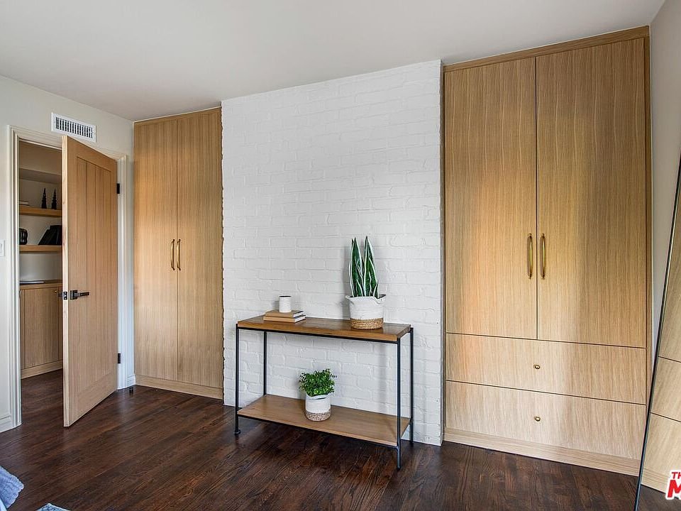 Wood cabinet with closed doors, wooden shelves, books, and decorative vases