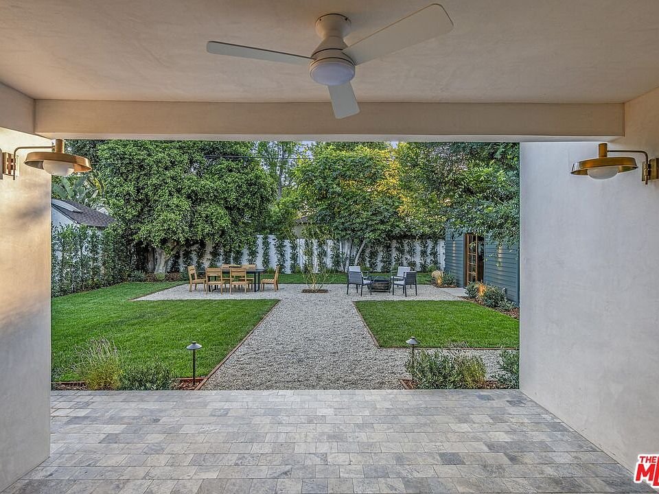 Backyard with grass, gravel path, garden furniture, and trees