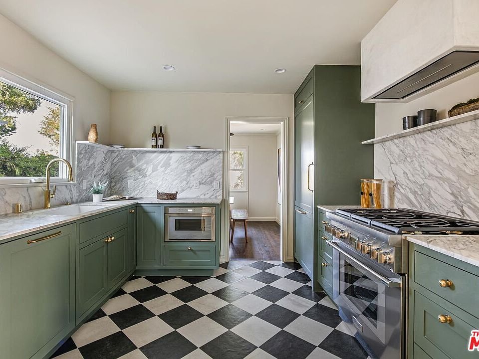 Kitchen with green cabinets, white marble countertops, and black and white checkered floor