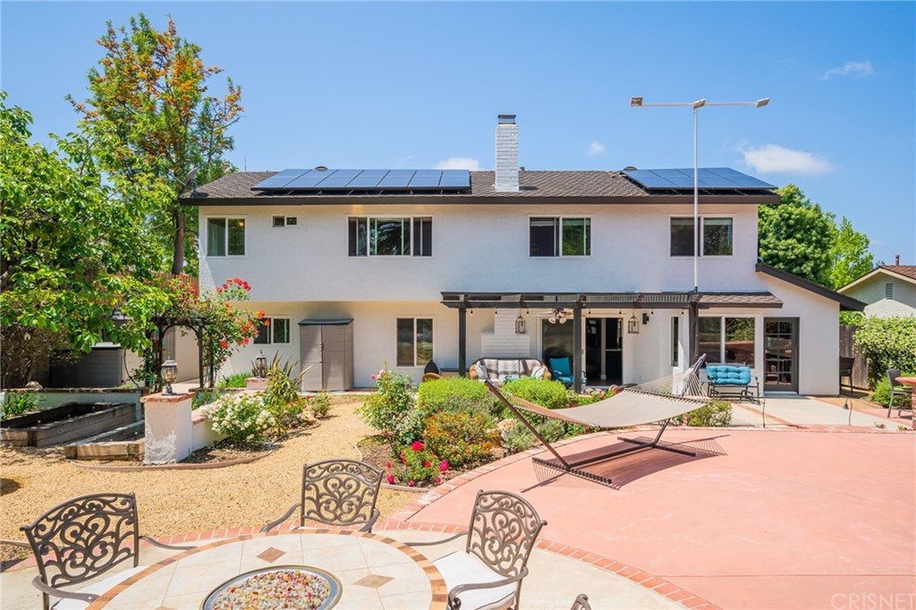 California real estate house with solar panels, garden, patio seating, hammock, and plants.