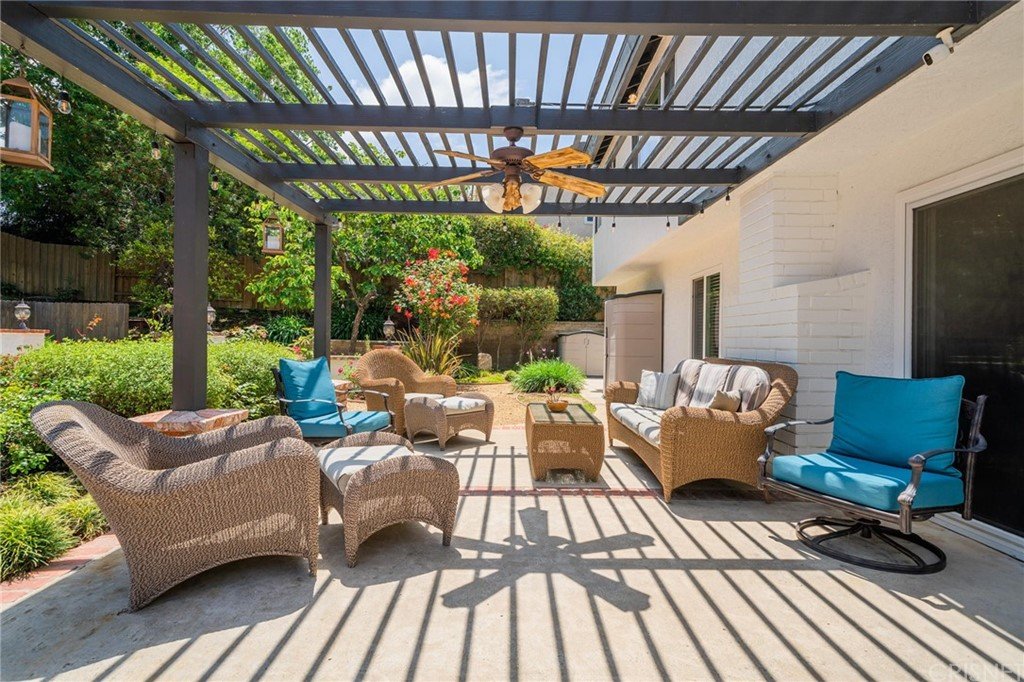 California real estate house patio with chairs, ceiling fan, and garden.