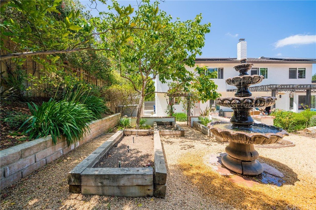 California real estate house garden with fountain, raised beds, and green plants.