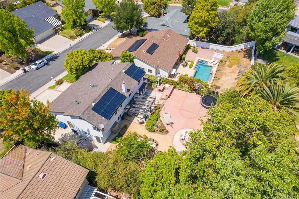 Aerial view of California real estate houses with solar panels, pool, and landscaped yards.