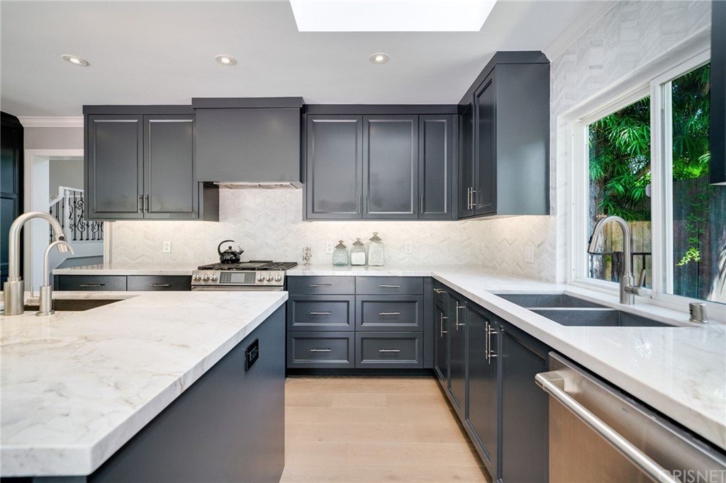 Kitchen with dark cabinets, marble counter, and stainless steel appliances.