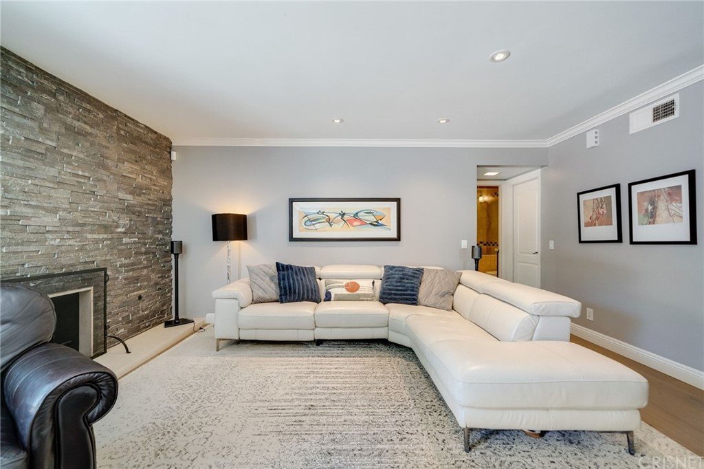 Living room with sectional sofa, stone wall, and wall art.