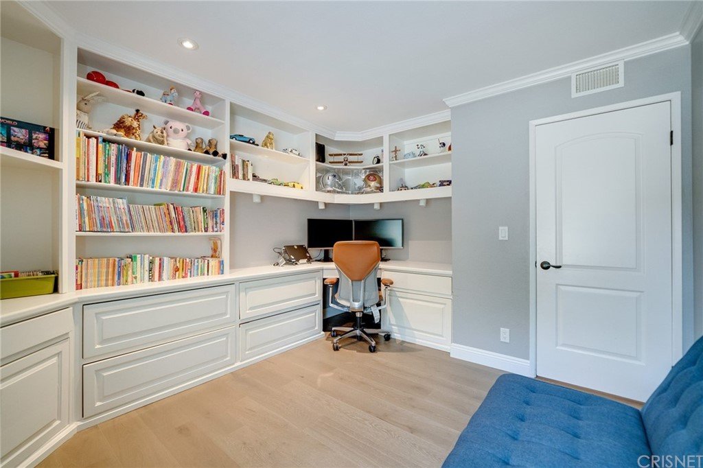 Home office with bookshelves, desk with computer, chair, blue sofa, and gray walls.