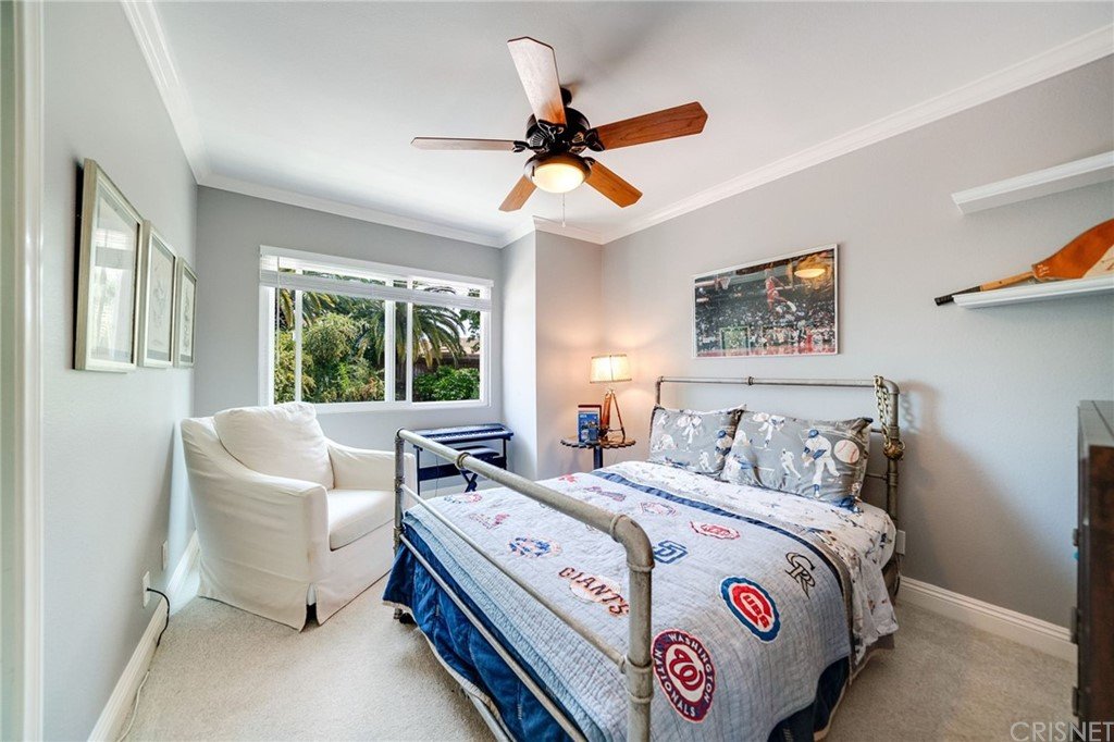 Bedroom with bed, ceiling fan, chair, and windows.