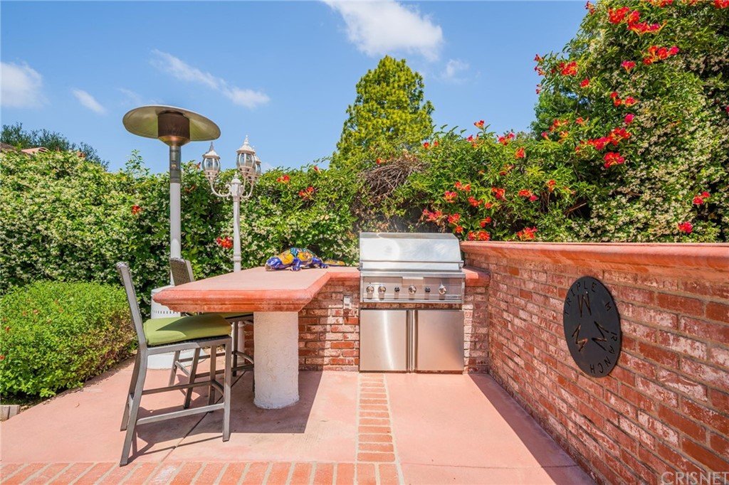 California real estate house patio with grill, seating, and green plants.