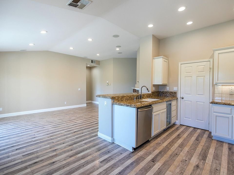 Open living area with kitchen, granite countertops, stainless steel appliances, dining table, and seating area