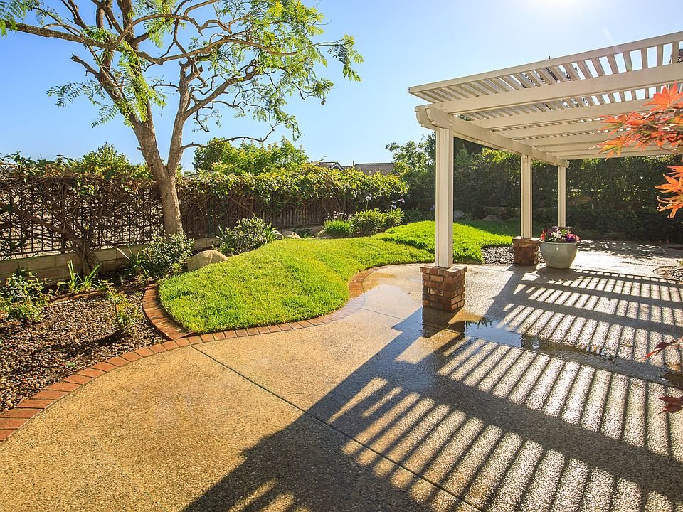 California real estate house backyard with green lawn, tree, and patio cover.