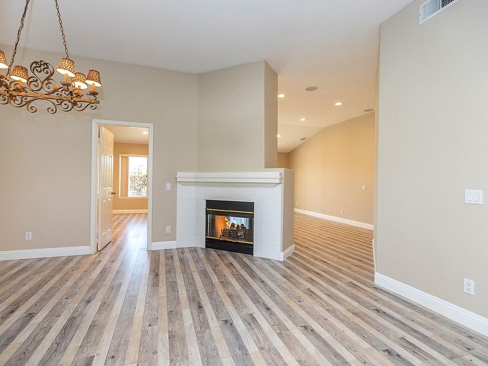 Living area with dining table, fireplace with TV, light walls, wood floor, and decorations