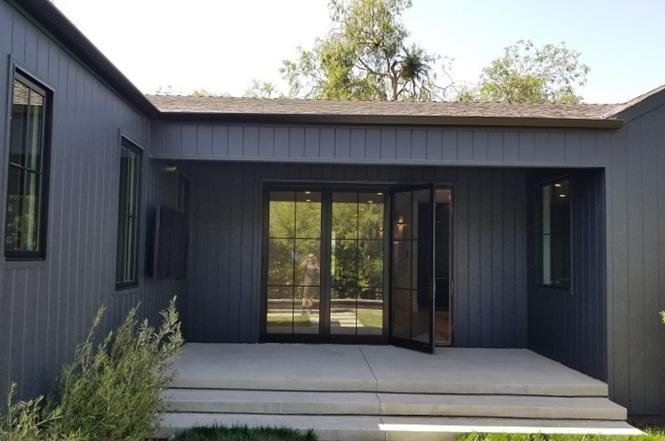 House exterior with dark wood siding, glass doors, and concrete entrance.