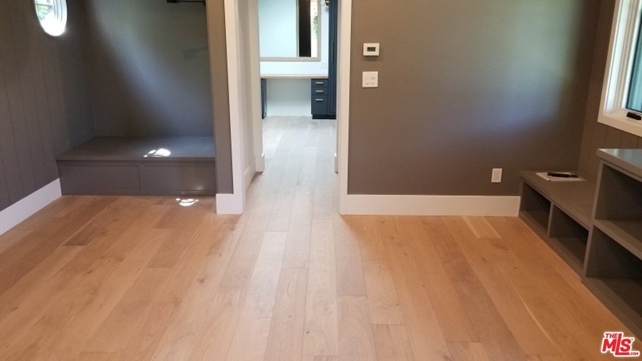 Spacious room with wooden floor, gray walls, and built-in shelf.