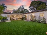 Luxury California real estate house backyard with green lawn, patio seating, and garden.