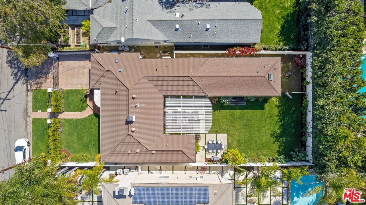 California real estate house aerial view with buildings, green lawn, patio, and outdoor furniture.